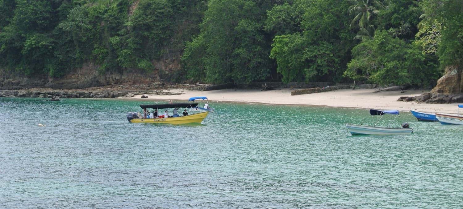 Boats on the waters of Panama near a rainforest shore, the route missionaries travel to reach remote villages